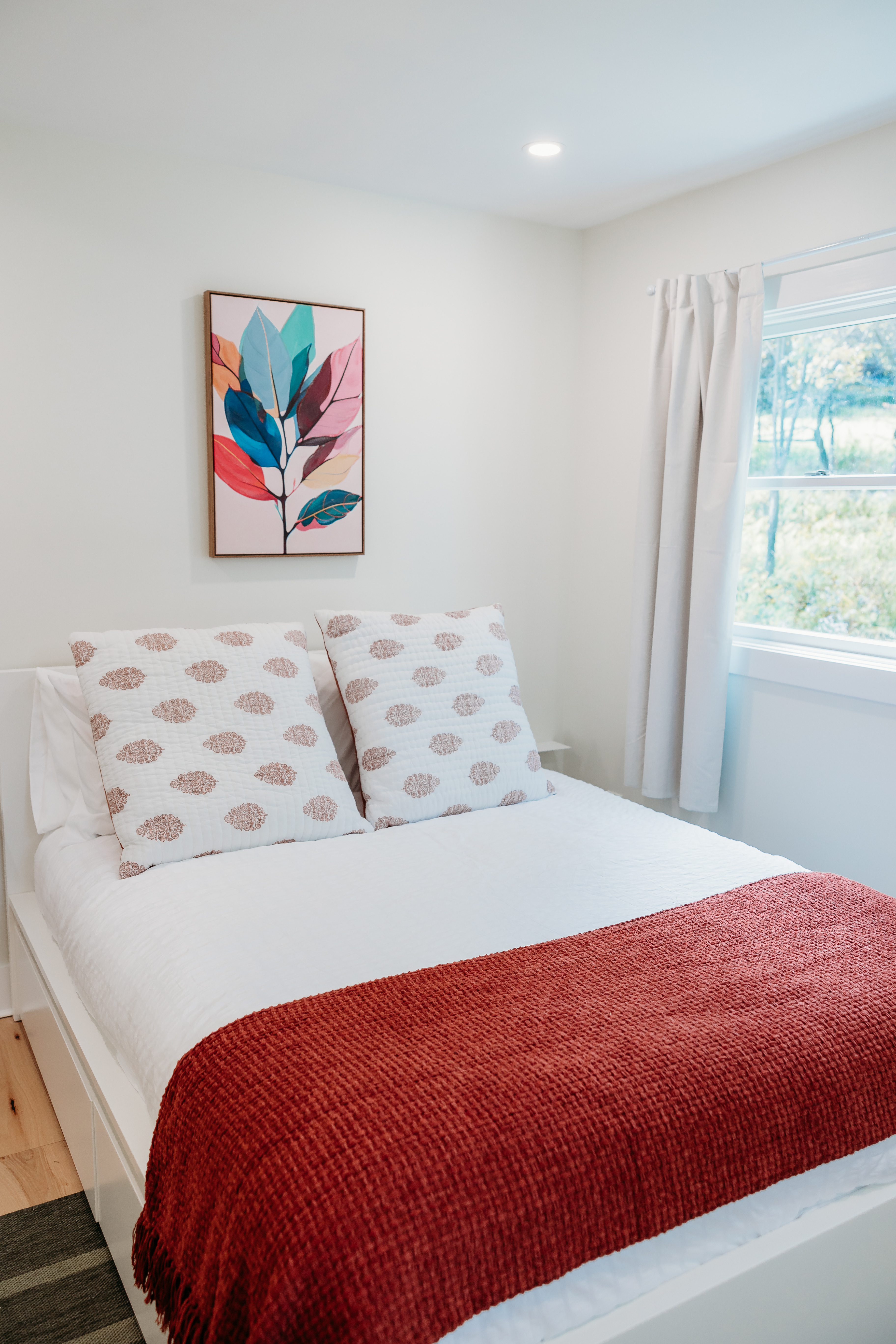 Bedroom with red throw and colorful art